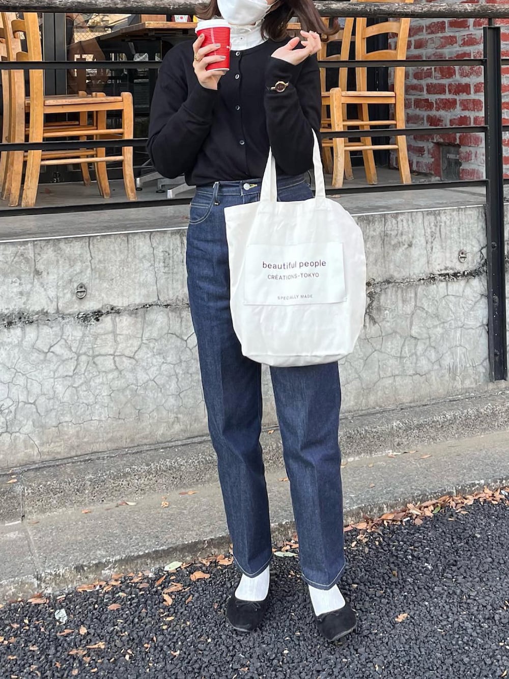 ブルー系のデニムパンツ、ホワイト系のトートバッグ、ブラック系のカーディガン/ボレロを着用したレディースの春コーディネートの3枚目の写真