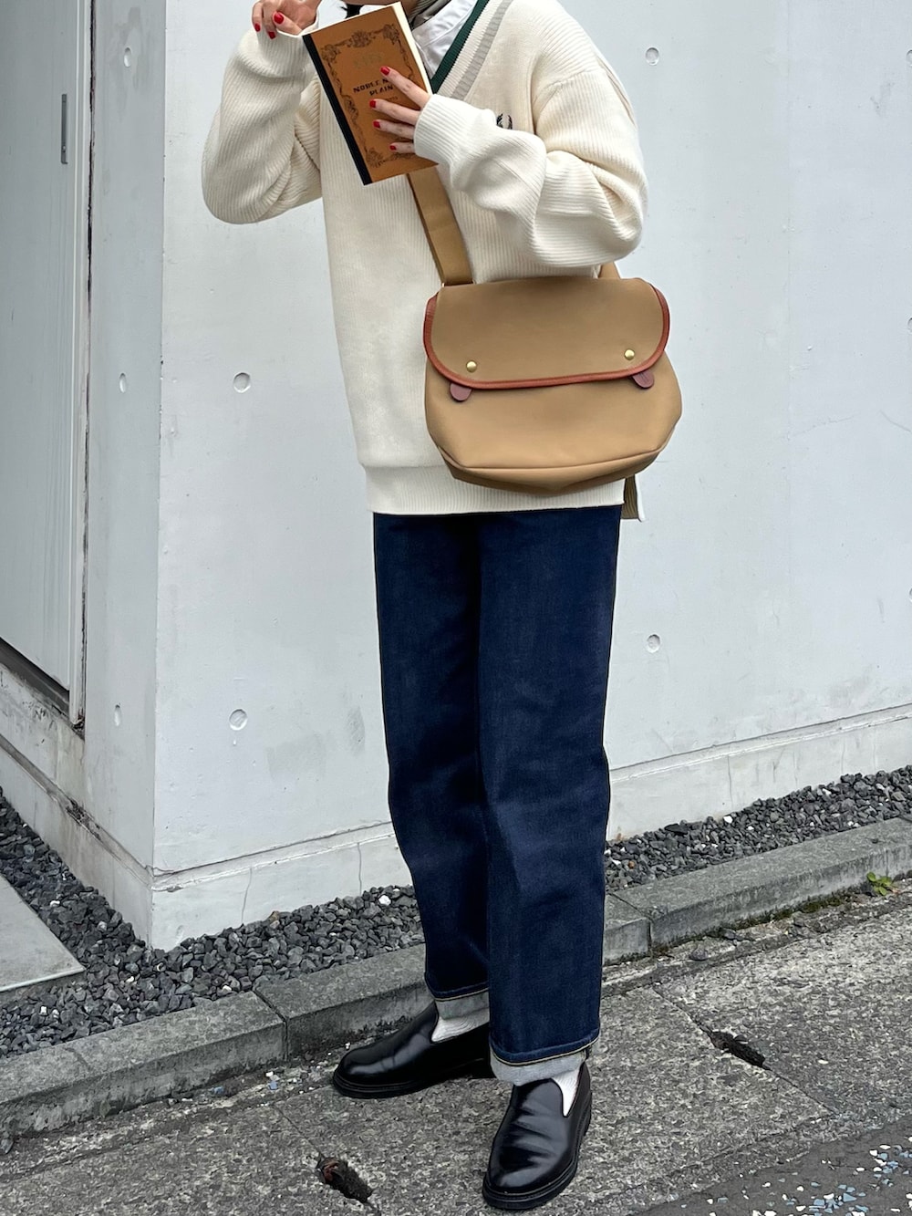 ベージュ系のショルダーバッグ、ホワイト系のニット/セーター、ブルー系のデニムパンツを着用したレディースの冬コーディネートの2枚目の写真