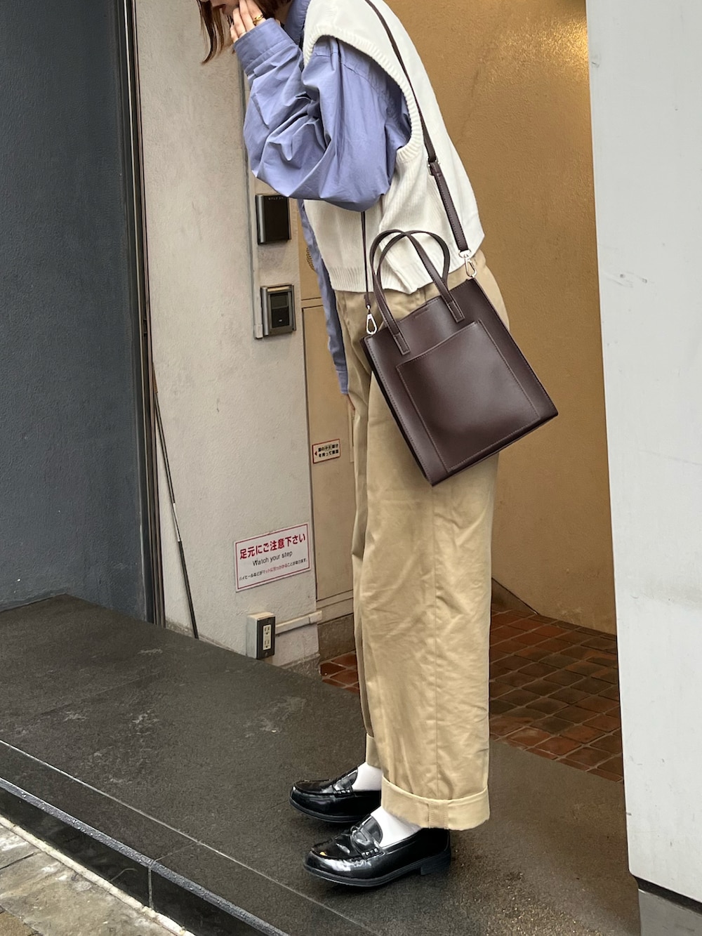 ブラウン系のショルダーバッグ、ブルー系のシャツ/ブラウス、ブラック系のチノパンツを着用したレディースの春コーディネートの4枚目の写真