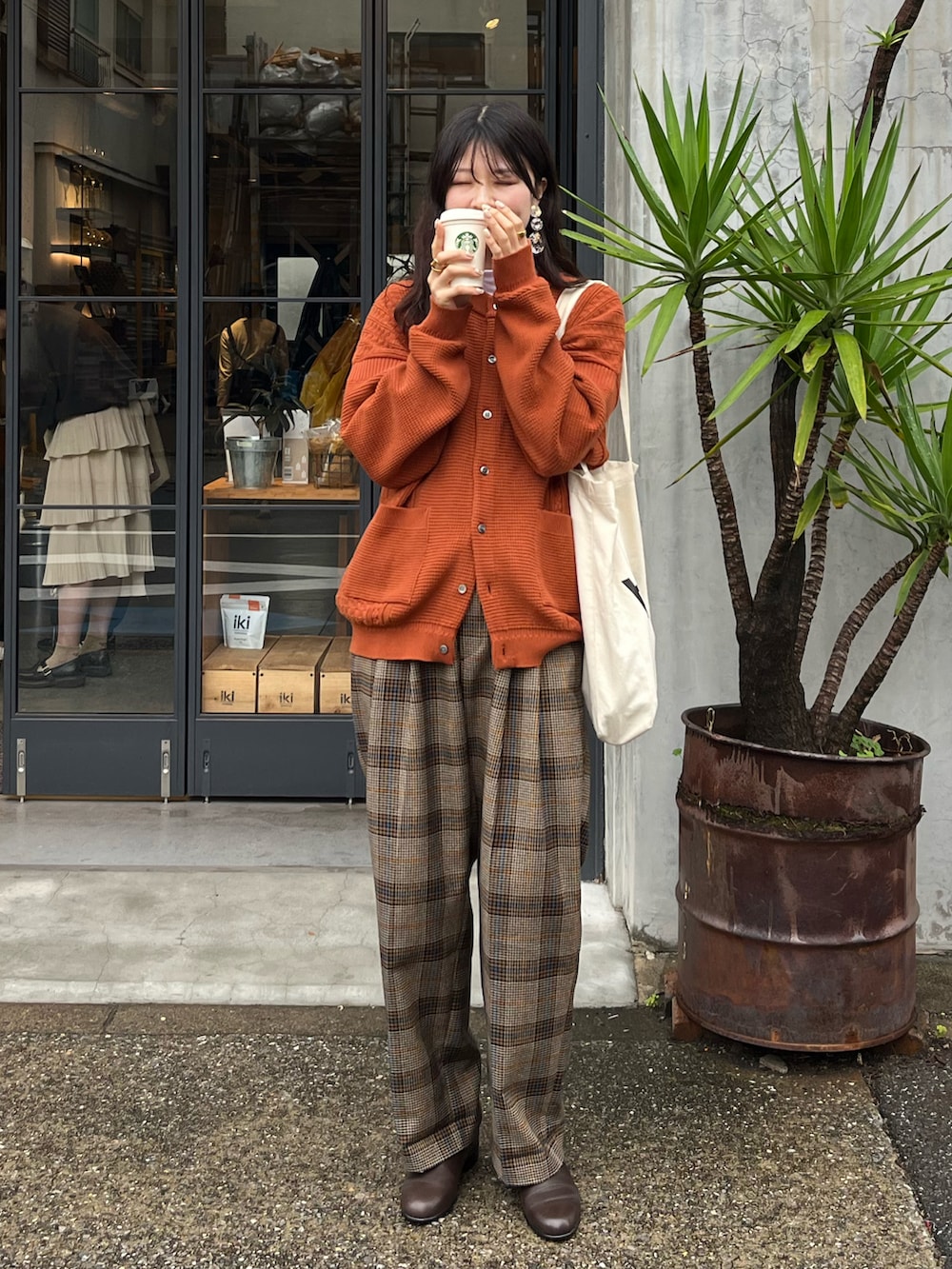 ブラウン系のドレスシューズ、ブラウン系のスラックス、ホワイト系のトートバッグを着用したレディースの秋コーディネートの3枚目の写真