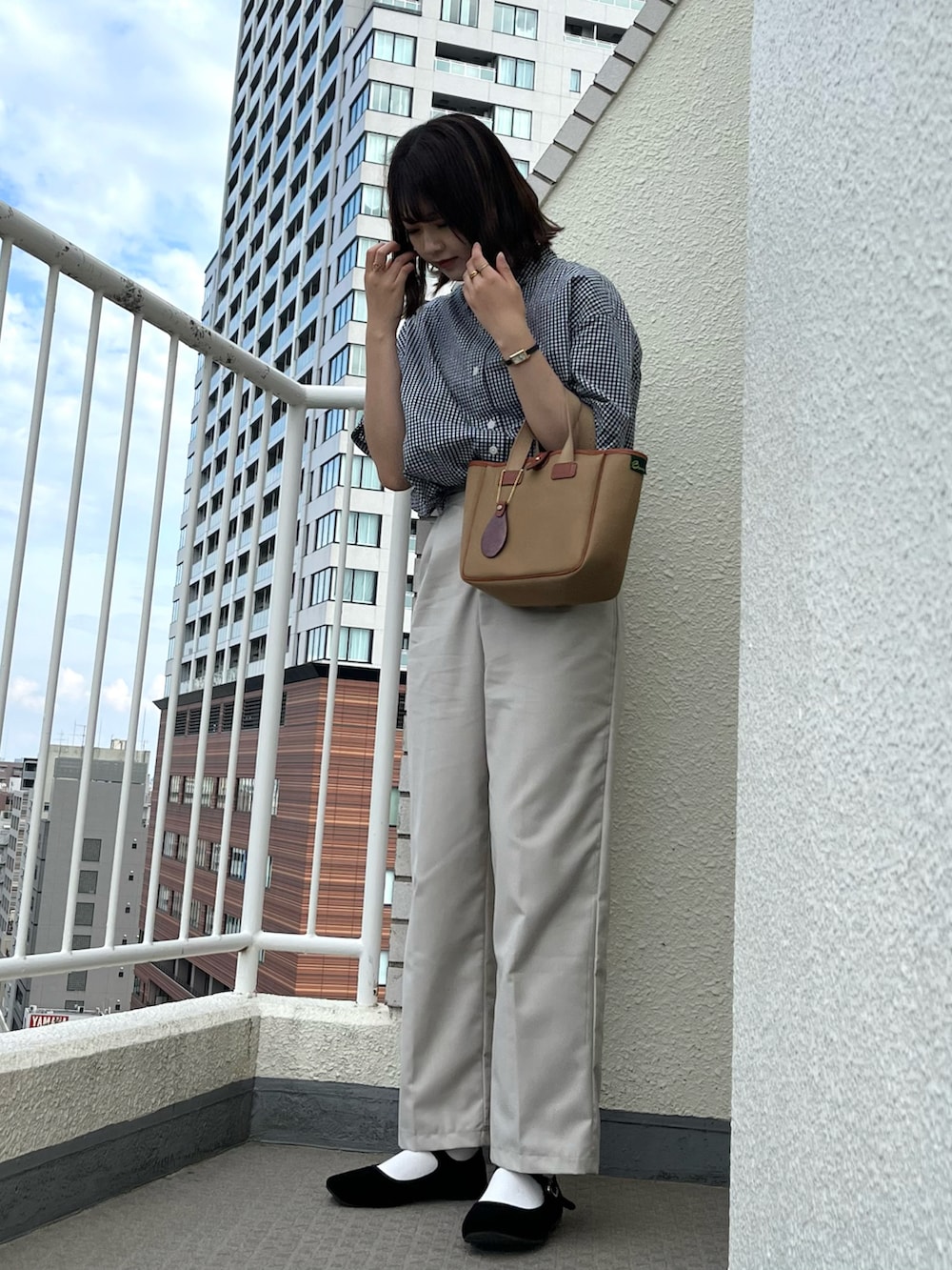 グリーン系のトートバッグ、ブラック系のシャツ/ブラウス、ホワイト系のパンツを着用したレディースの春コーディネートの2枚目の写真