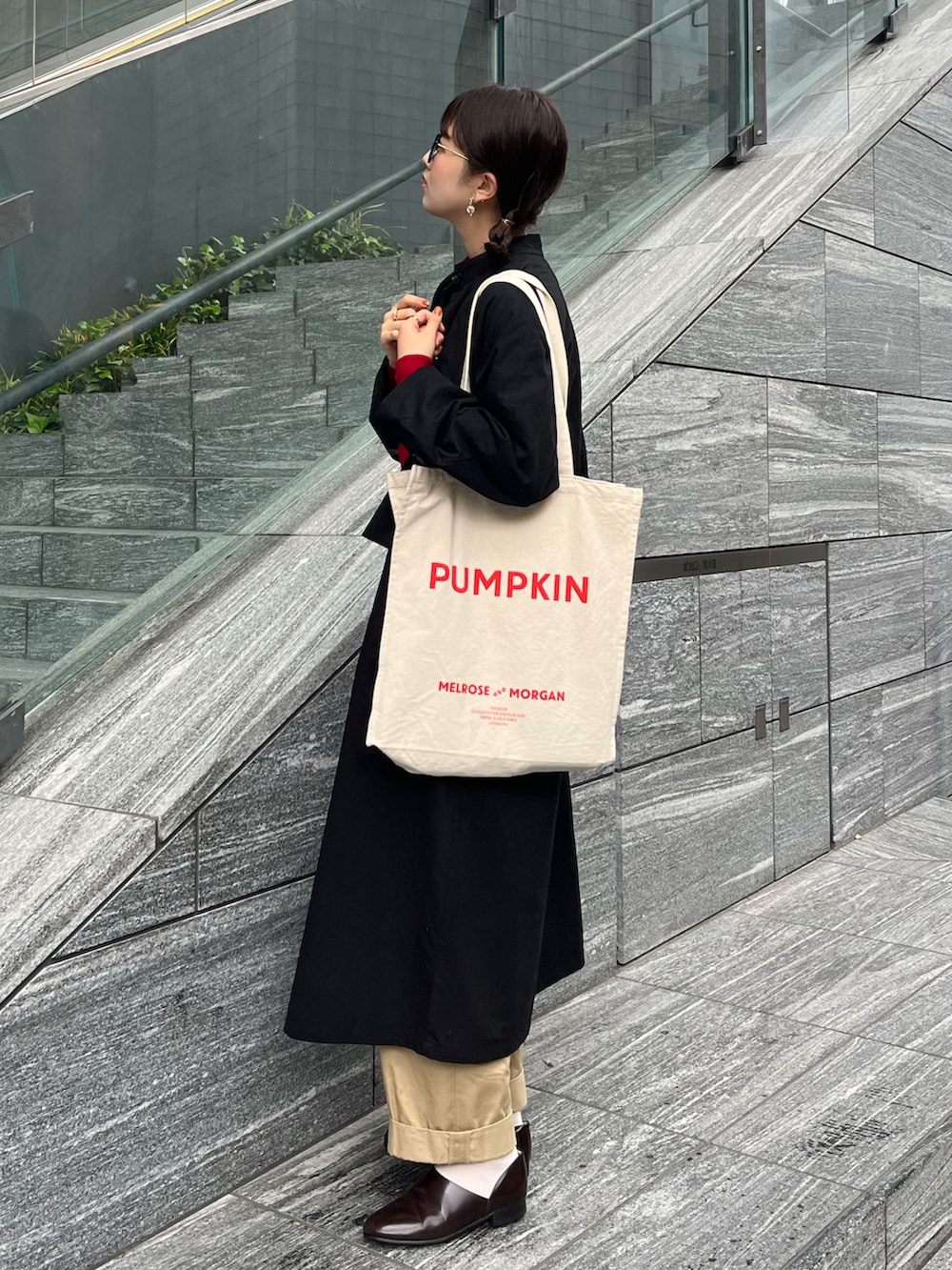 ブラウン系のドレスシューズ、ベージュ系のチノパンツ、ブラック系のトレンチコートを着用したレディースの冬コーディネートの2枚目の写真