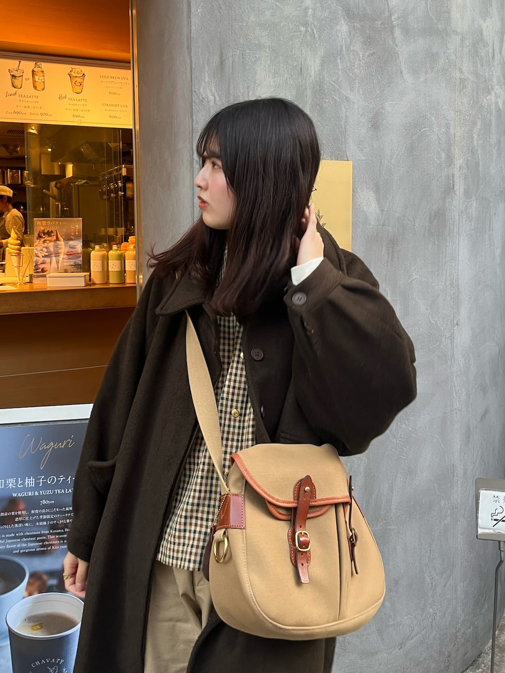 ブラウン系のステンカラーコート、グリーン系のショルダーバッグ、ベージュ系のシャツ/ブラウスを着用したレディースの秋コーディネートの2枚目の写真