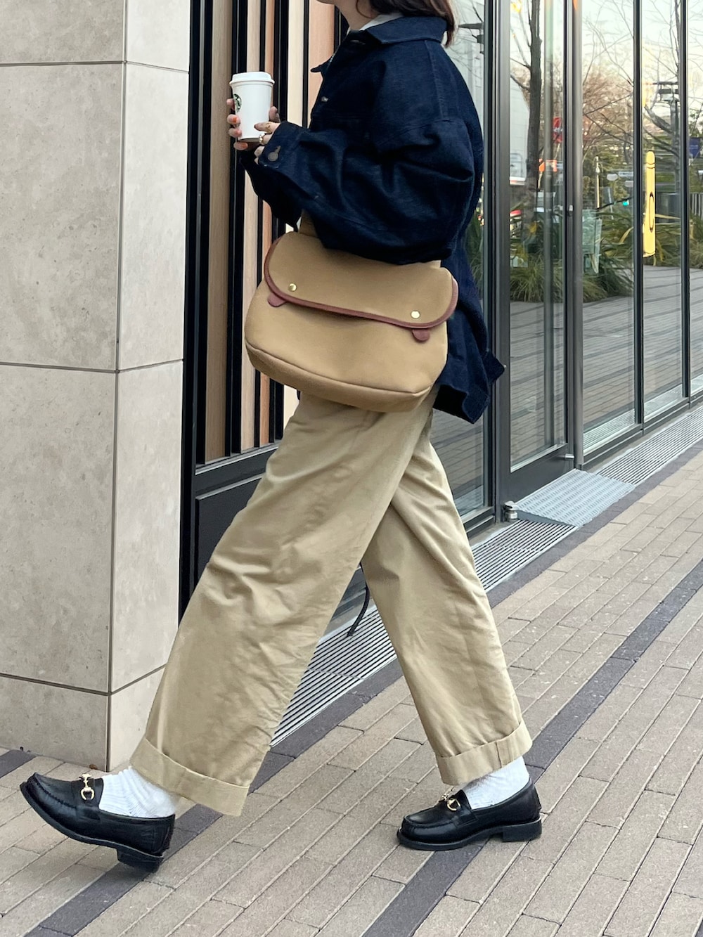 ブラック系のローファー、ホワイト系のシャツ/ブラウス、ベージュ系のショルダーバッグを着用したレディースの春コーディネートの2枚目の写真