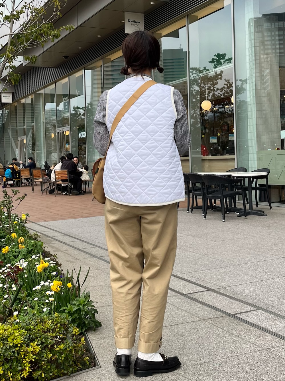 ホワイト系のベスト、ベージュ系のショルダーバッグ、ベージュ系のチノパンツを着用したレディースの春コーディネートの2枚目の写真