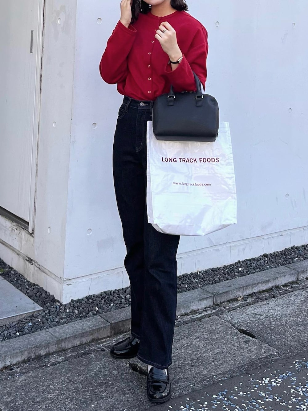 レッド系のカーディガン/ボレロ、ブルー系のデニムパンツ、ブラック系のローファーを着用したレディースの秋コーディネートの2枚目の写真