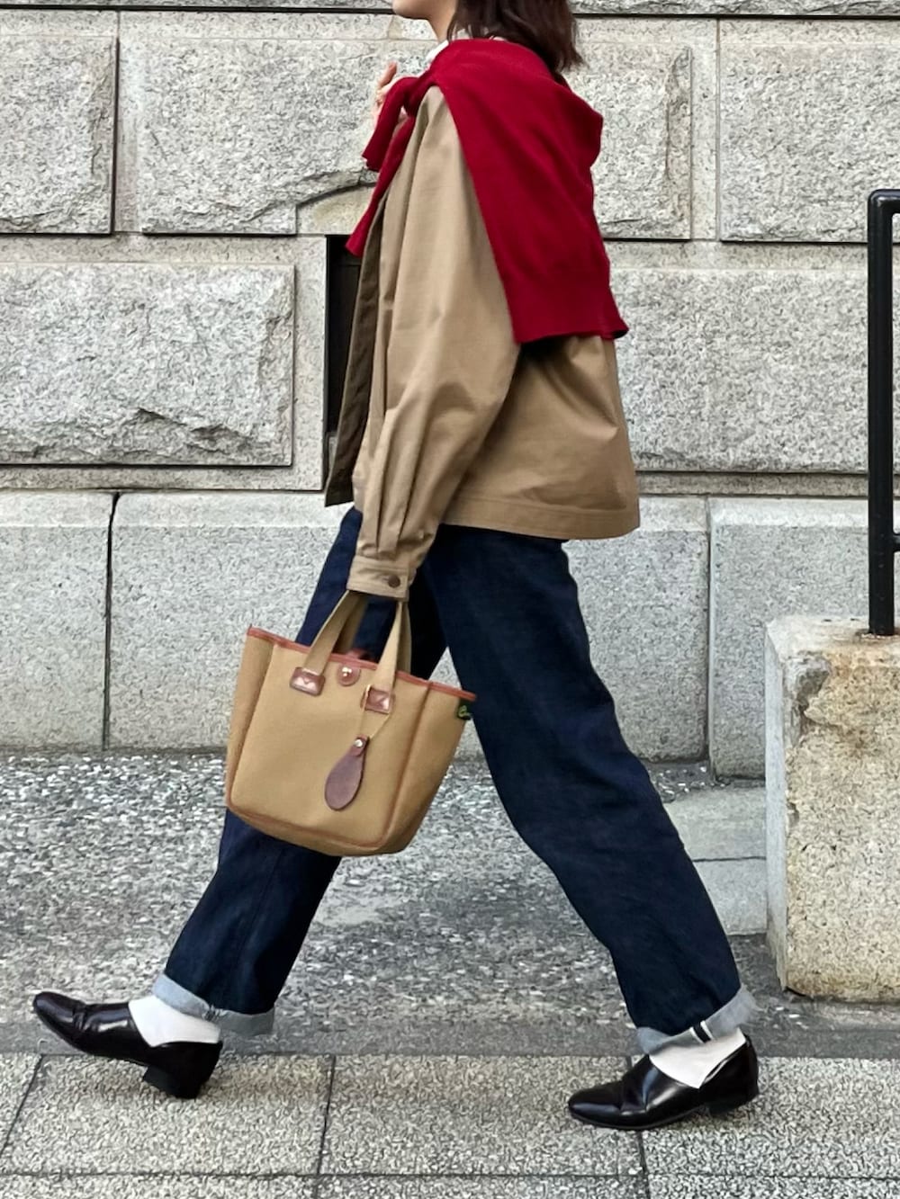 ブルー系のデニムパンツ、グリーン系のトートバッグ、レッド系のニット/セーターを着用したレディースの冬コーディネートの2枚目の写真