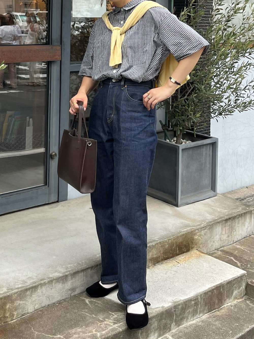 ブルー系のデニムパンツ、ブラウン系のショルダーバッグ、ブラック系のシャツ/ブラウスを着用したレディースの夏コーディネートの2枚目の写真