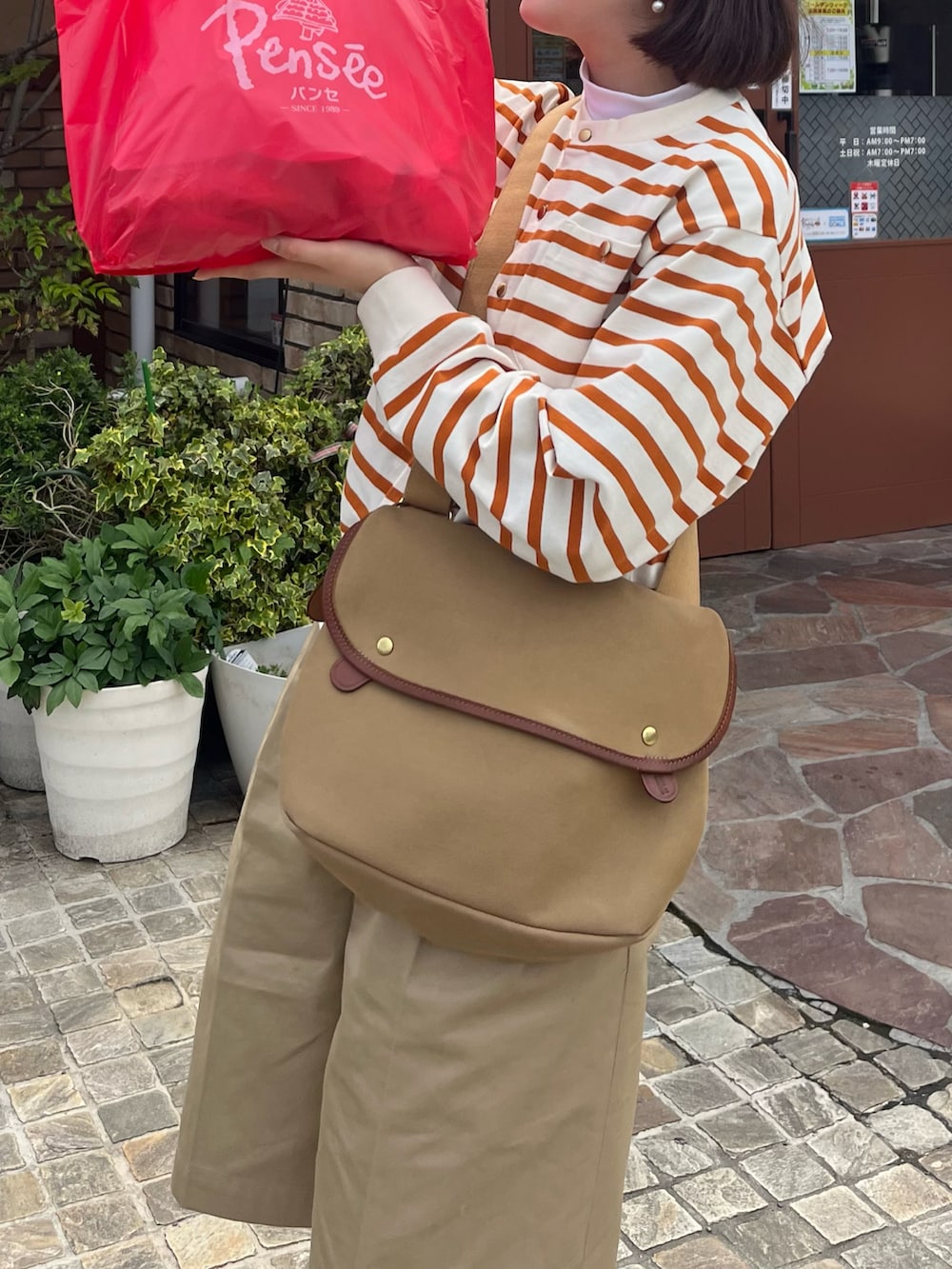 ブラウン系のローファー、ベージュ系のチノパンツ、ベージュ系のショルダーバッグを着用したレディースの春コーディネートの2枚目の写真