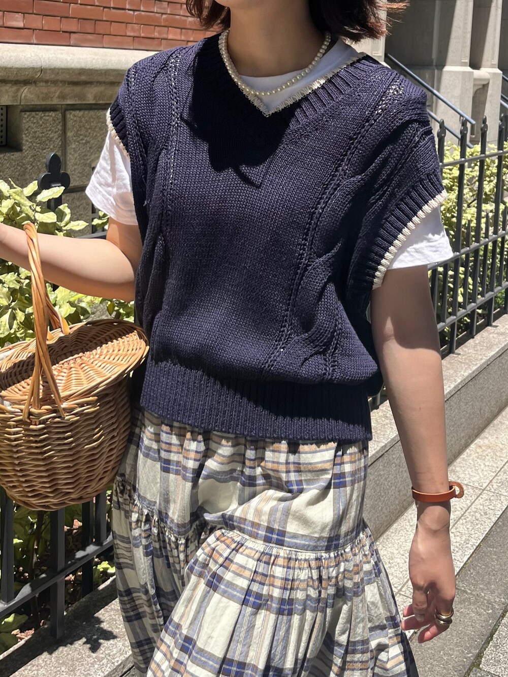 ブラウン系のローファー、ブルー系のニット/セーター、ホワイト系のスカートを着用したレディースの夏コーディネートの2枚目の写真