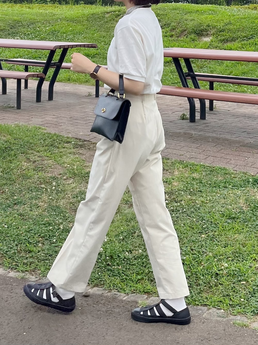 ブラック系のサンダル、ブラック系のショルダーバッグ、ホワイト系のTシャツ/カットソーを着用したレディースの夏コーディネートの2枚目の写真