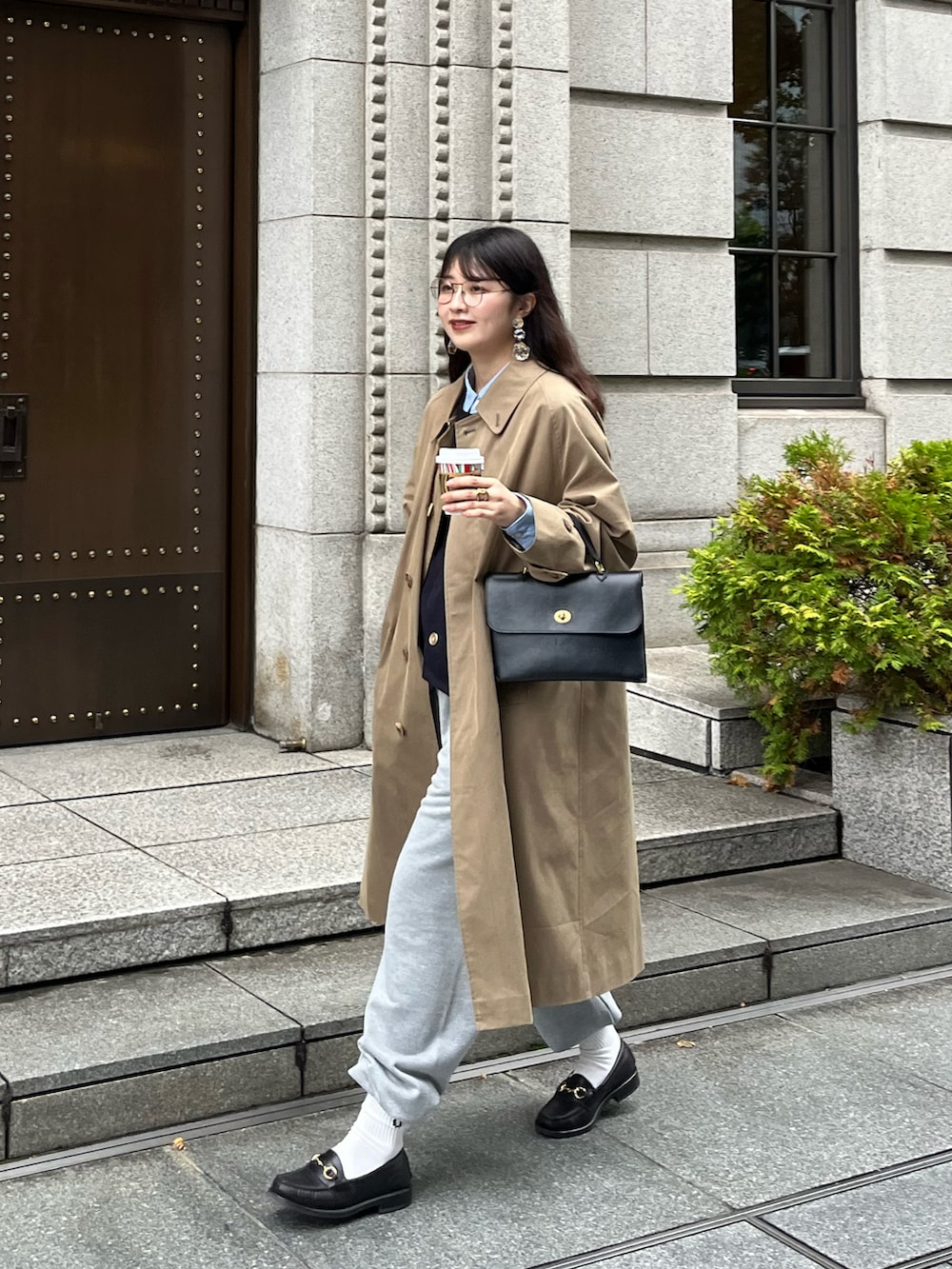 ブラック系のショルダーバッグ、ブルー系のベスト、グレー系のスウェットパンツを着用したレディースの秋コーディネートの2枚目の写真