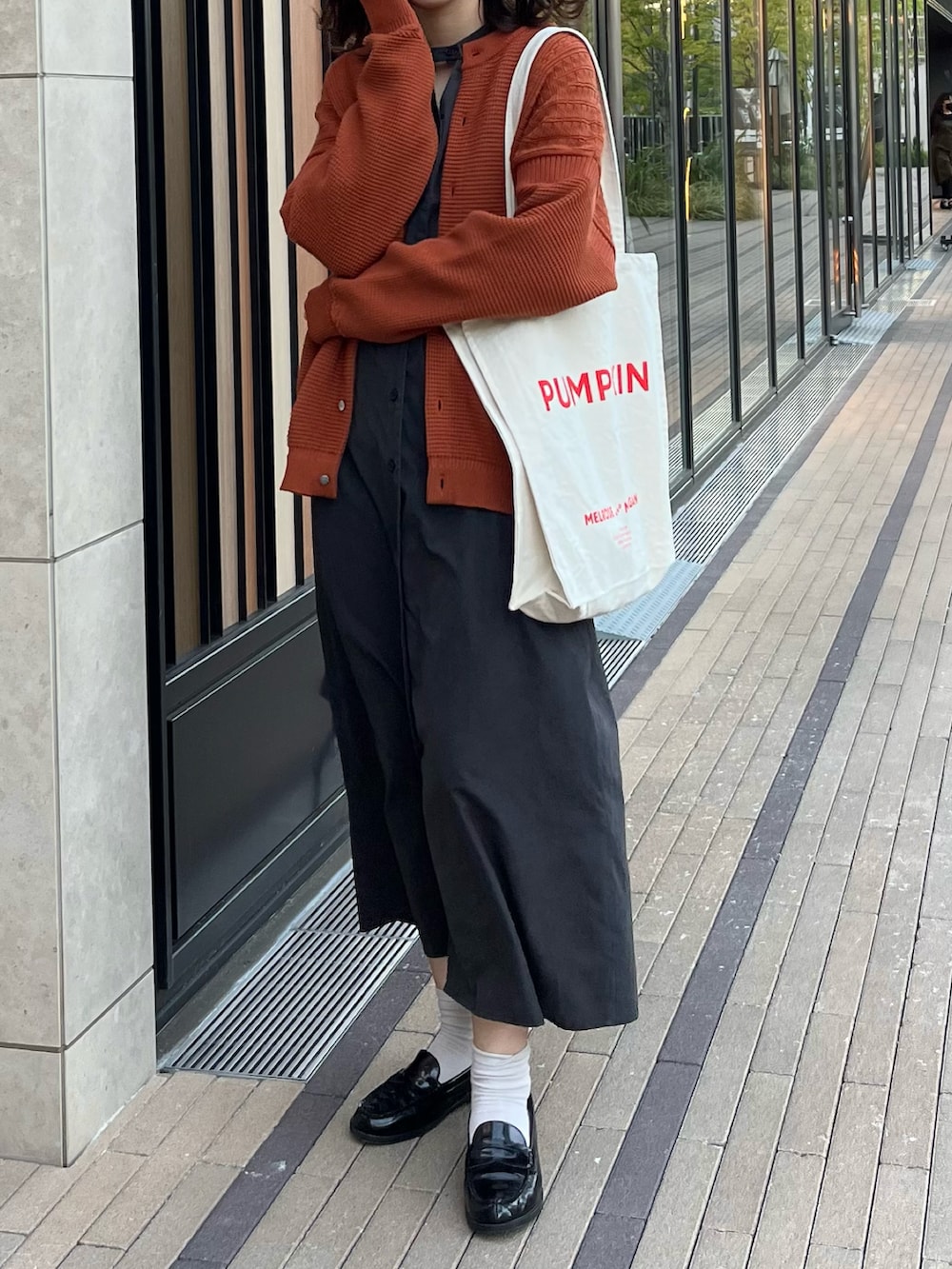 ブラック系のワンピース、オレンジ系のカーディガン/ボレロ、ブラック系のローファーを着用したレディースの秋コーディネートの2枚目の写真