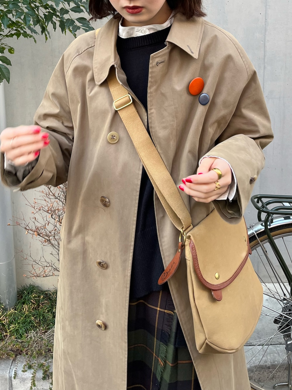 ホワイト系のベスト、ベージュ系のショルダーバッグ、グリーン系のスカートを着用したレディースの冬コーディネートの2枚目の写真