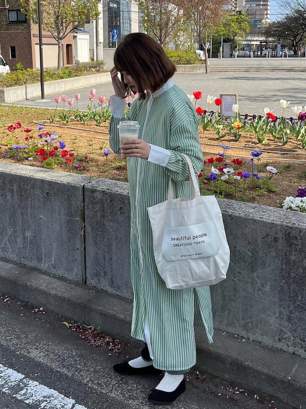 ブラック系のバレエシューズ、ホワイト系のトートバッグ、グリーン系のワンピースを着用したレディースの春コーディネートの4枚目の写真