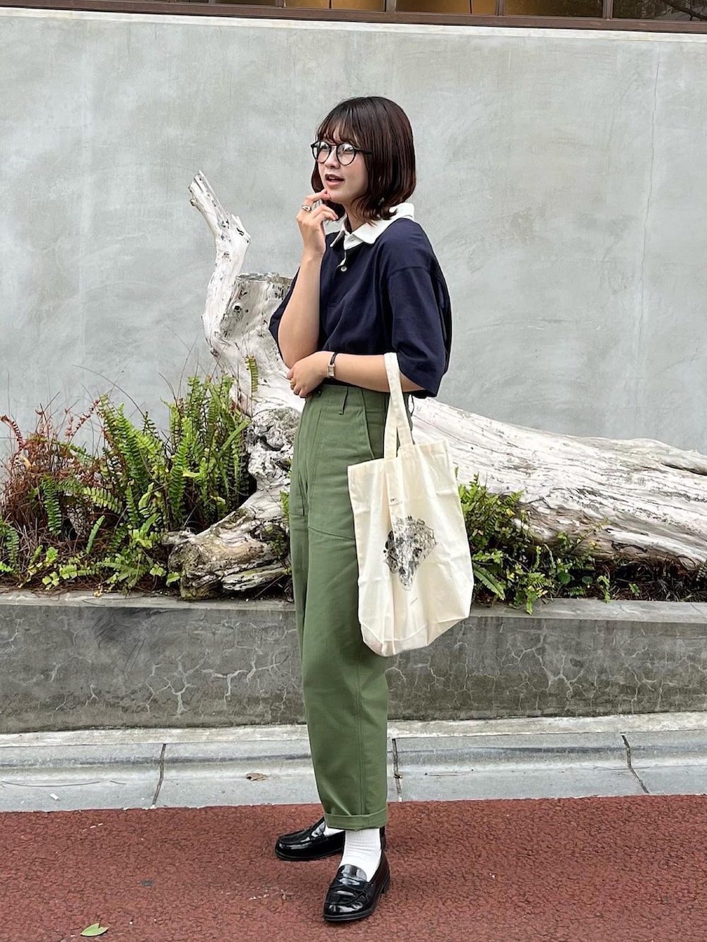 ブルー系のポロシャツ、ホワイト系のバッグ、グリーン系のその他パンツを着用したレディースの夏コーディネートの2枚目の写真