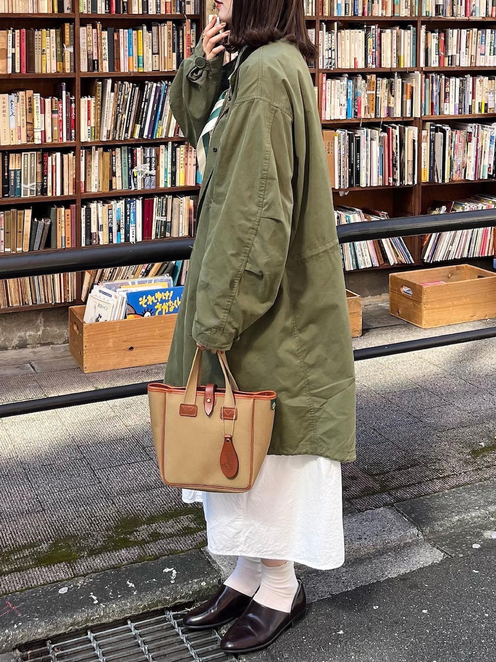 グリーン系のモッズコート、ホワイト系のワンピース、グリーン系のトートバッグを着用したレディースの秋コーディネートの2枚目の写真