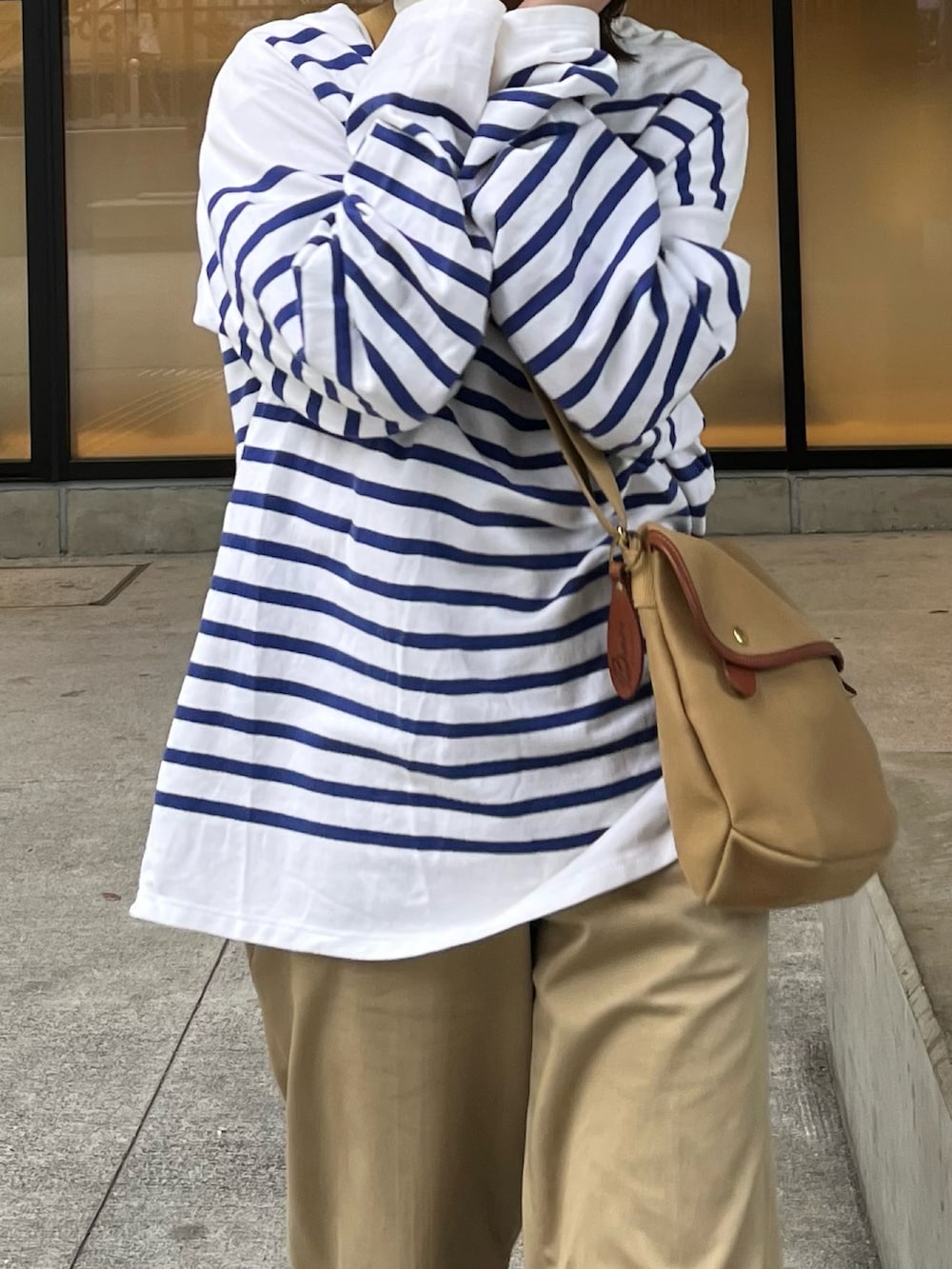 ベージュ系のショルダーバッグ、ブルー系のTシャツ/カットソー、ベージュ系のチノパンツを着用したレディースの春コーディネートの5枚目の写真