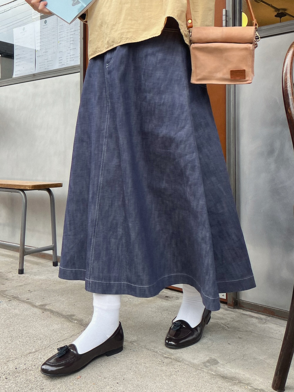 ブルー系のスカート、ブラック系のバレエシューズ、ベージュ系のショルダーバッグを着用したレディースの冬コーディネートの2枚目の写真