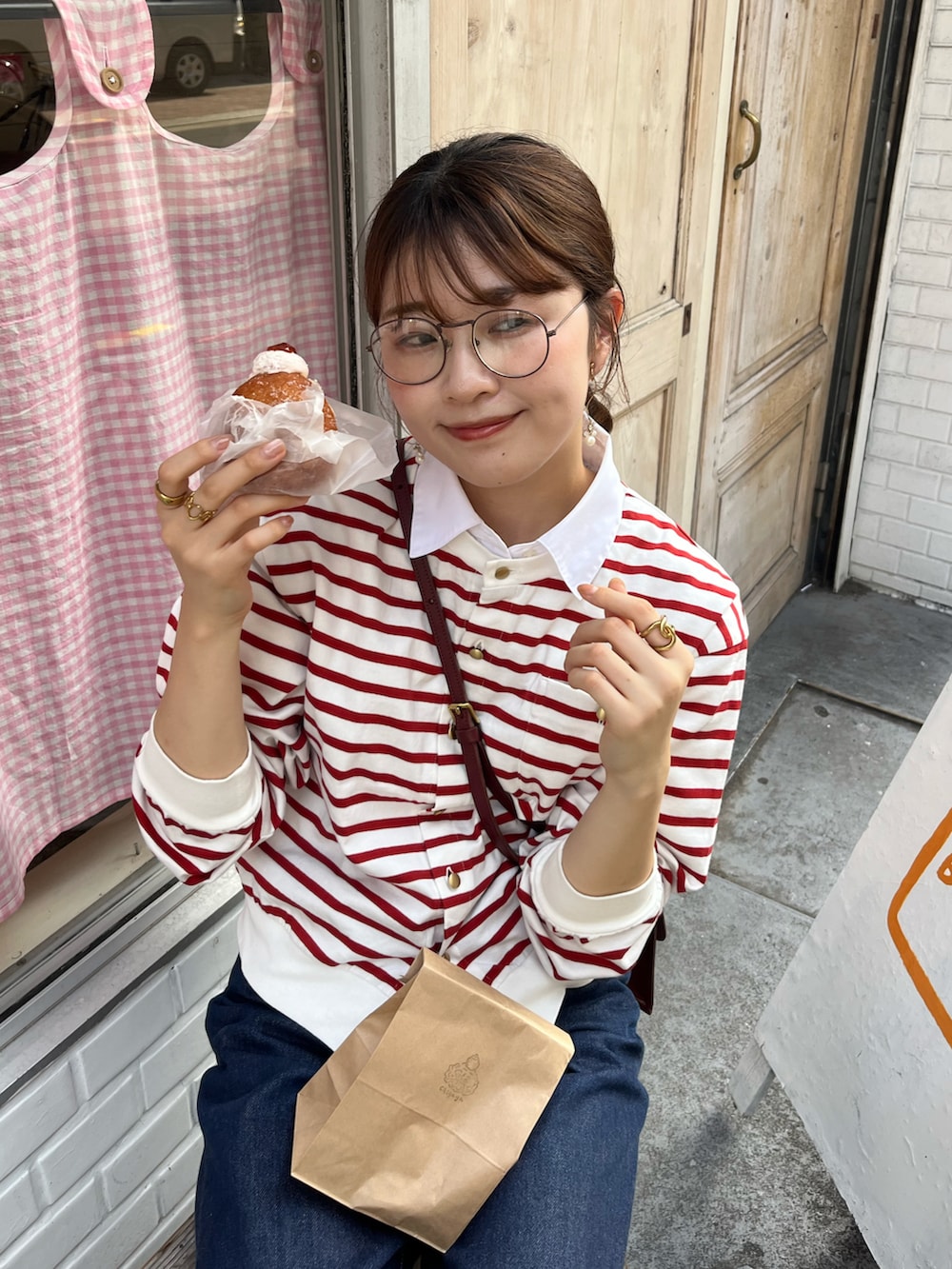 ブルー系のデニムパンツ、ブラック系のバレエシューズ、レッド系のショルダーバッグを着用したレディースの夏コーディネートの2枚目の写真