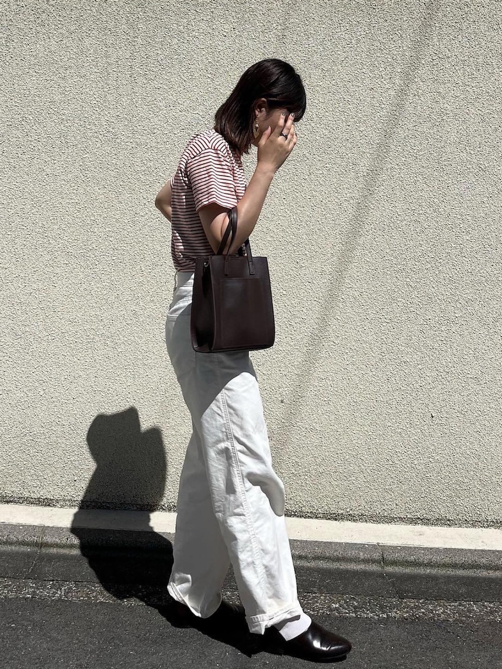 ブラウン系のドレスシューズ、ホワイト系のデニムパンツ、ブラウン系のショルダーバッグを着用したレディースの夏コーディネートの2枚目の写真