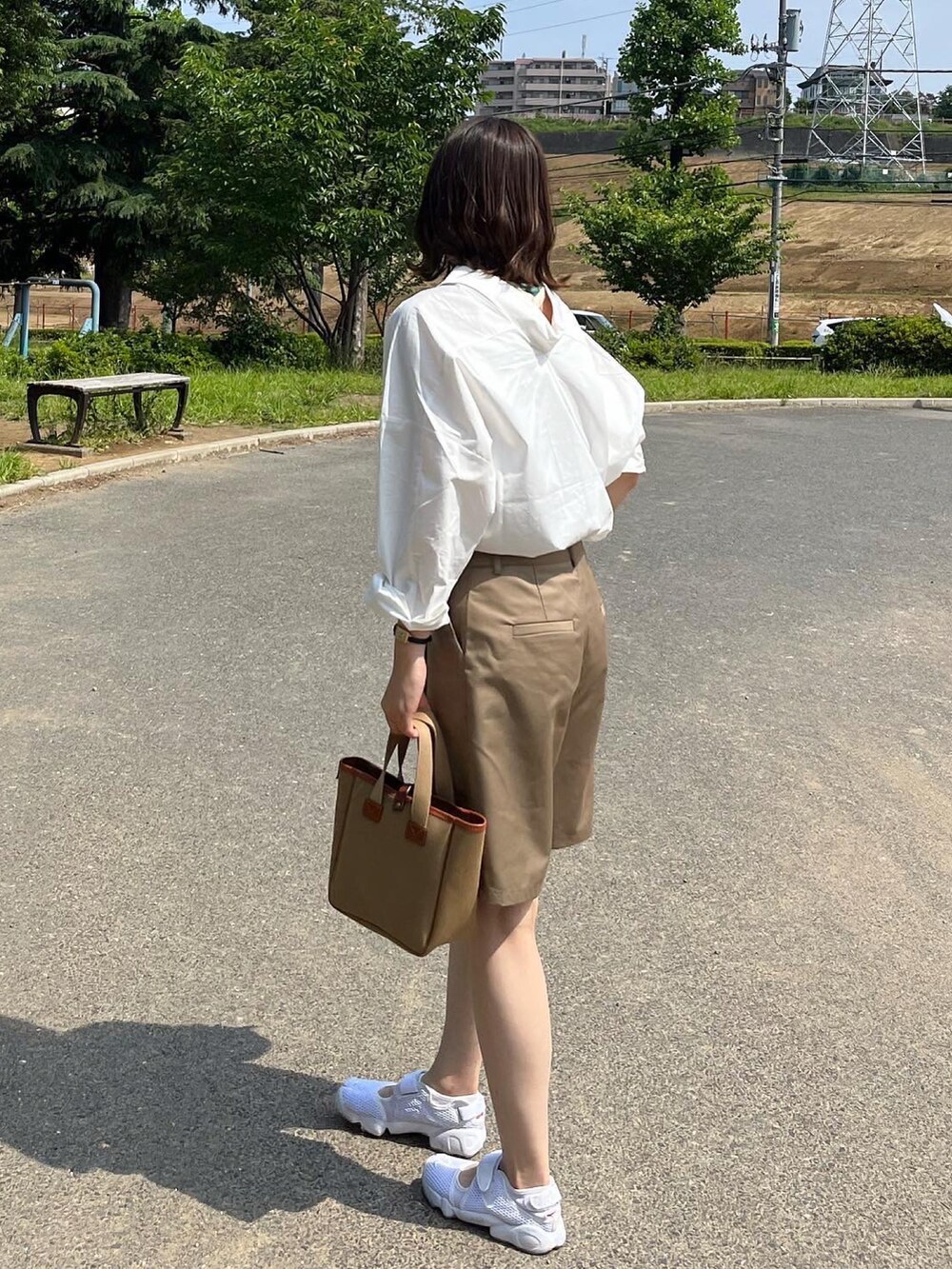 ベージュ系のスラックス、グリーン系のトートバッグ、ホワイト系のシャツ/ブラウスを着用したレディースの夏コーディネートの2枚目の写真