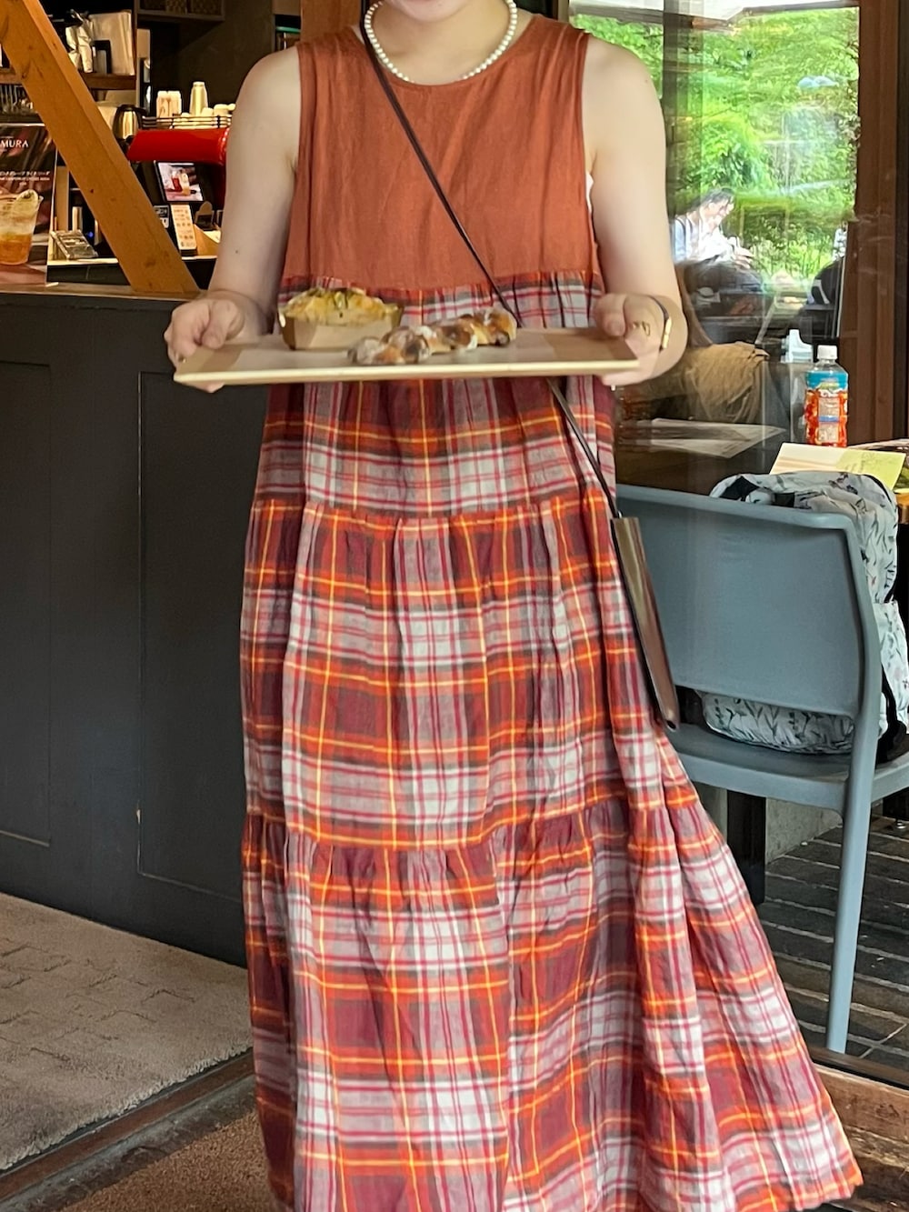 レッド系のワンピース、ブラウン系のショルダーバッグ、ブラウン系のローファーを着用したレディースの夏コーディネートの2枚目の写真