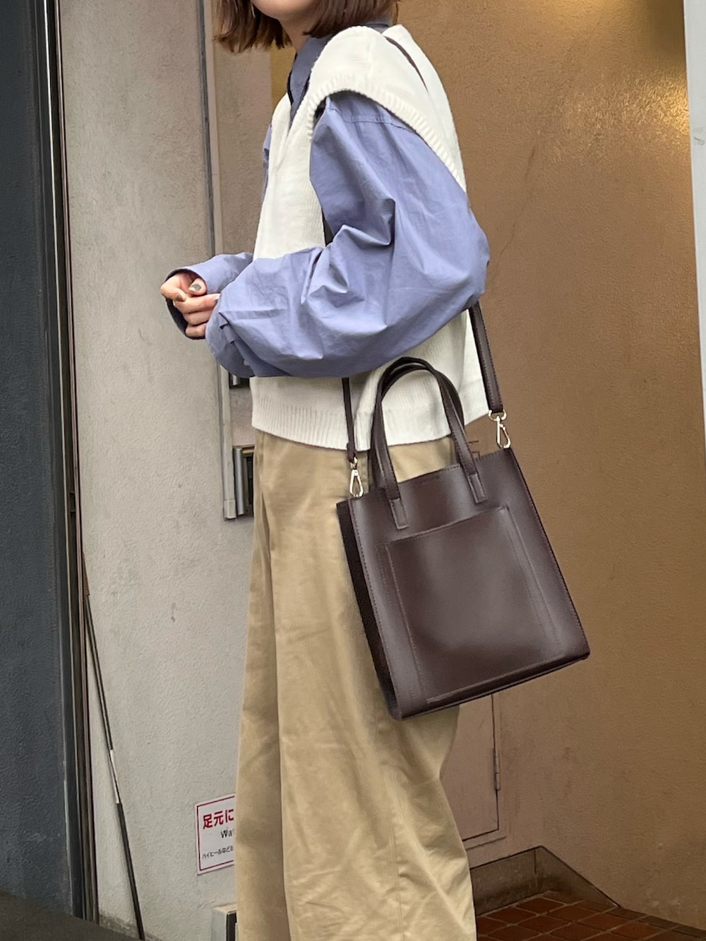 ブラウン系のショルダーバッグ、ブルー系のシャツ/ブラウス、ブラック系のチノパンツを着用したレディースの春コーディネートの3枚目の写真