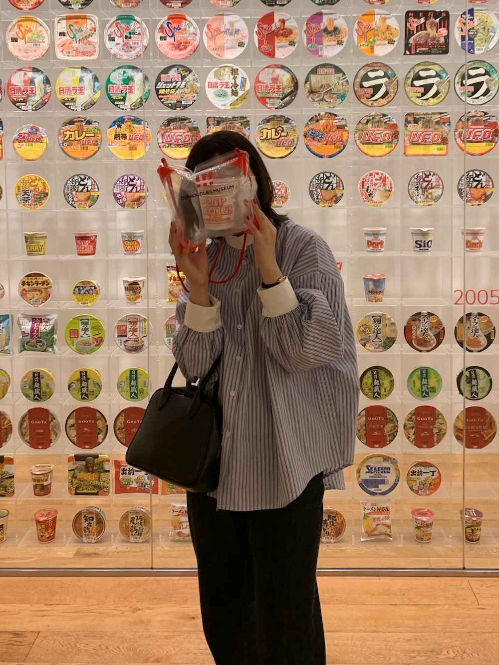 ブルー系のシャツ/ブラウス、ブルー系のデニムパンツ、ブラック系のハンドバッグを着用したレディースの春コーディネートの4枚目の写真