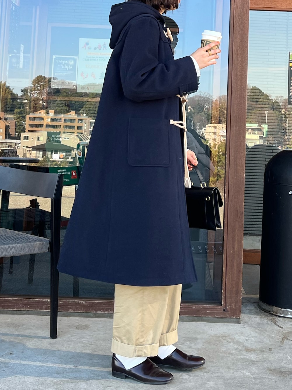 ブラウン系のドレスシューズ、ブラック系のショルダーバッグ、ブルー系のダッフルコートを着用したレディースの冬コーディネートの2枚目の写真