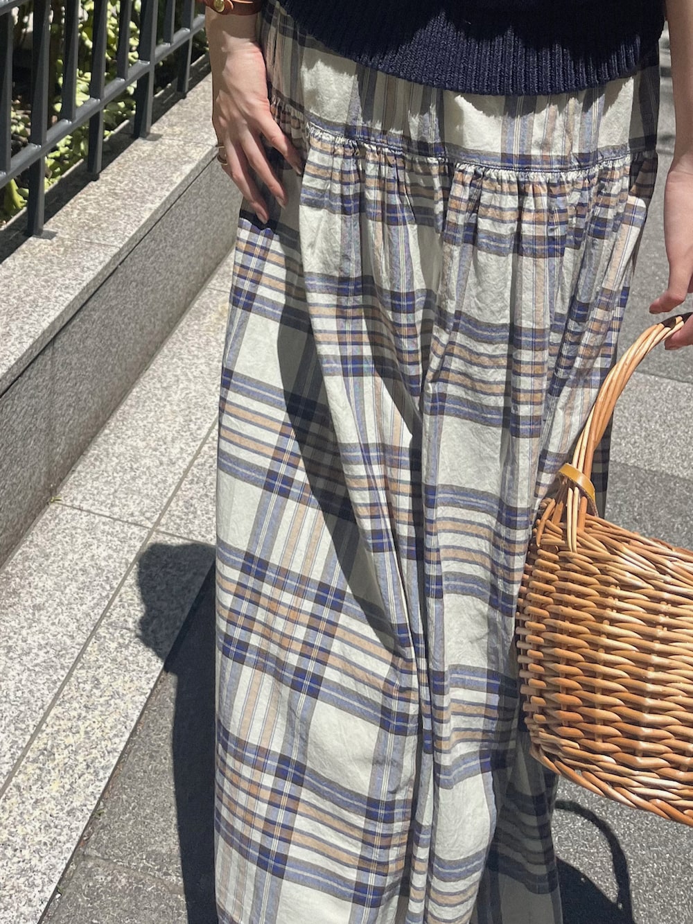 ブラウン系のローファー、ブルー系のニット/セーター、ホワイト系のスカートを着用したレディースの夏コーディネートの3枚目の写真