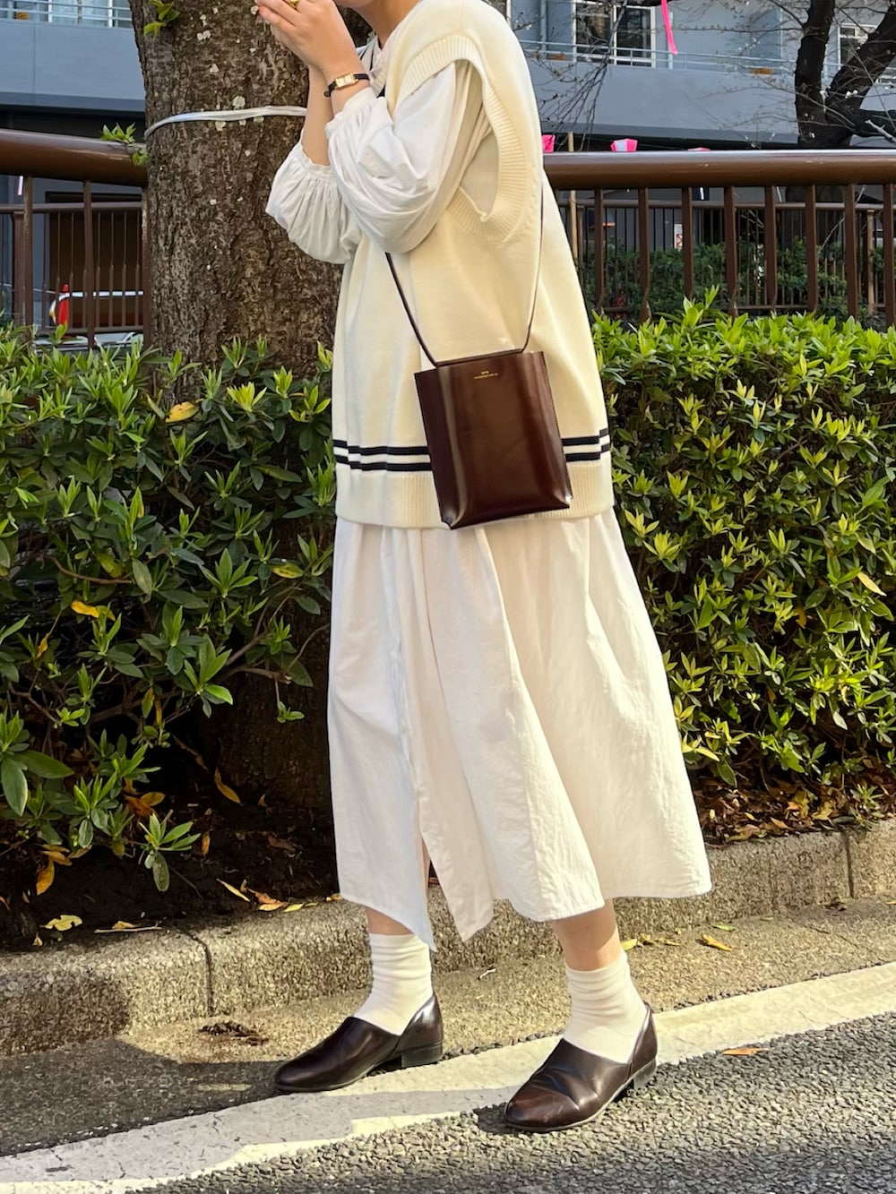 ホワイト系のベスト、ブラウン系のショルダーバッグ、ホワイト系のシャツワンピースを着用したレディースの春コーディネートの2枚目の写真