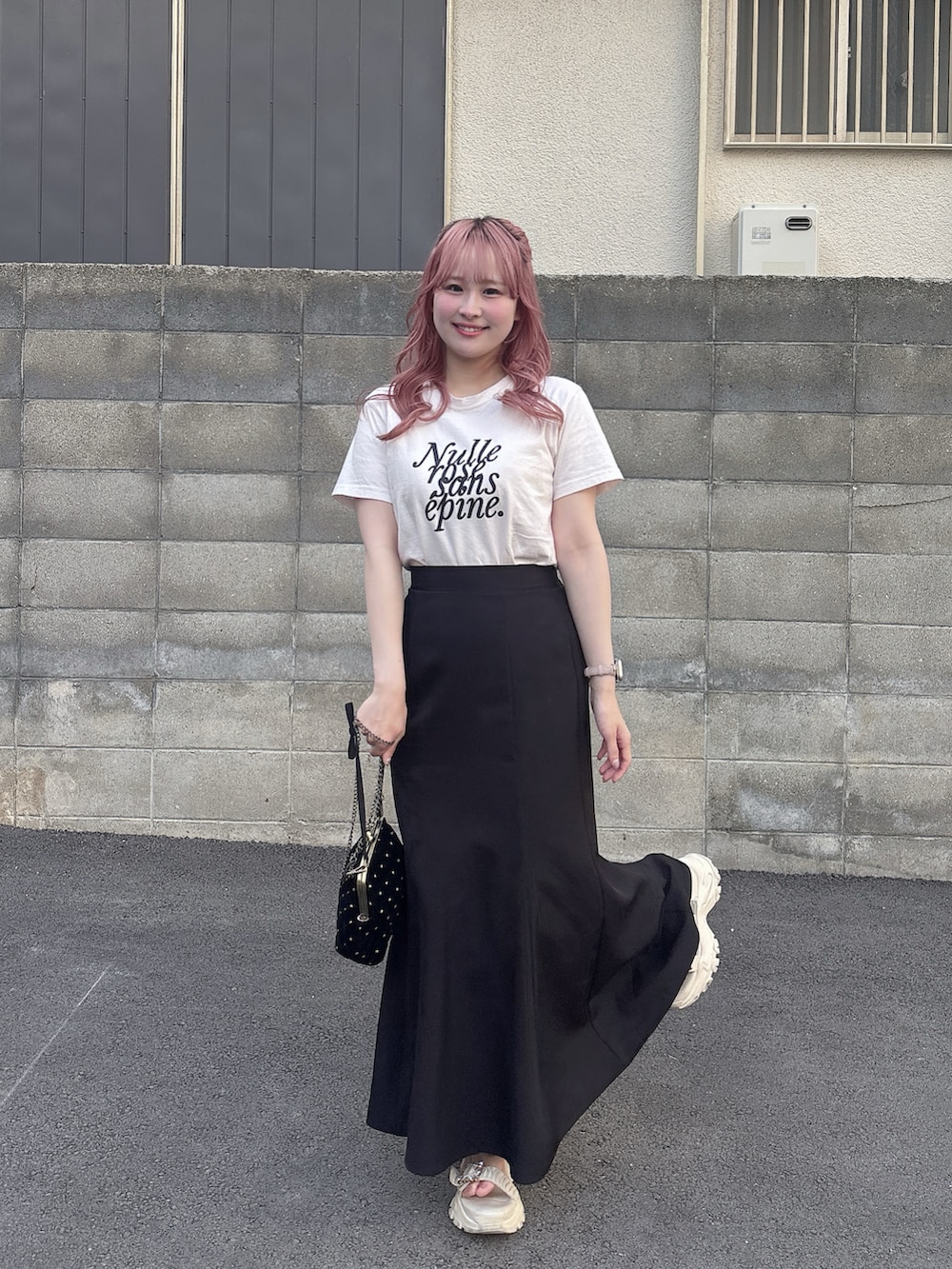 ブラック系のスカート、ピンク系のTシャツ/カットソー、ブラック系のショルダーバッグを着用したレディースの春コーディネートの2枚目の写真