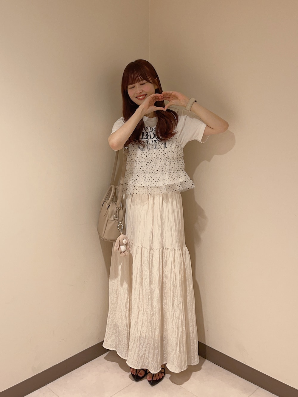 グレー系のショルダーバッグ、ホワイト系のスカート、その他のTシャツ/カットソーを着用したレディースの夏コーディネートの2枚目の写真