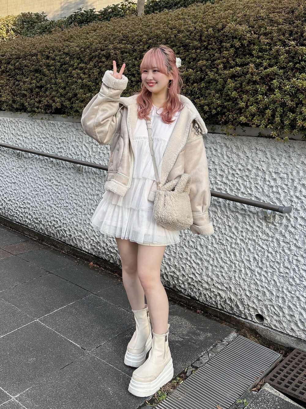 ピンク系のTシャツ/カットソー、ホワイト系のその他アウター、ベージュ系のバッグを着用したレディースの冬コーディネートの2枚目の写真