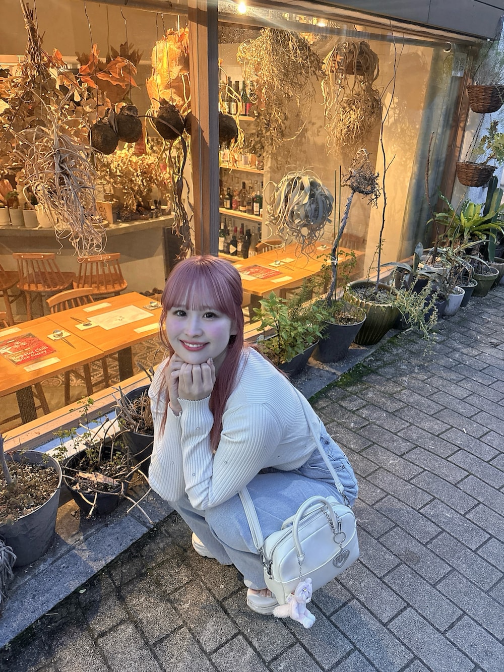 ブルー系のデニムパンツ、ホワイト系のショルダーバッグ、ホワイト系のニット/セーターを着用したレディースの春コーディネートの2枚目の写真