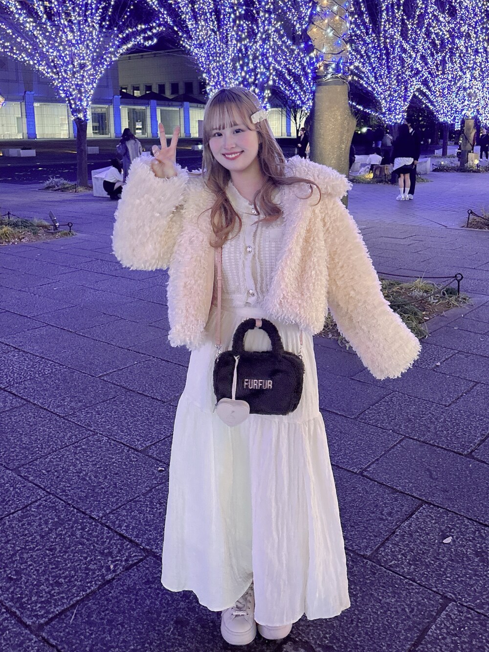 ピンク系のスニーカー、グレー系のボストンバッグ、ホワイト系のスカートを着用したレディースの冬コーディネートの2枚目の写真