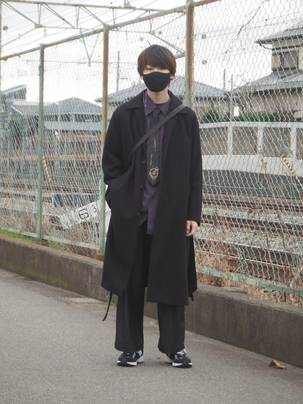 ブラック系のチェスターコート、ブルー系のデニムパンツ、ブラック系のスニーカーを着用したメンズの冬コーディネートの4枚目の写真