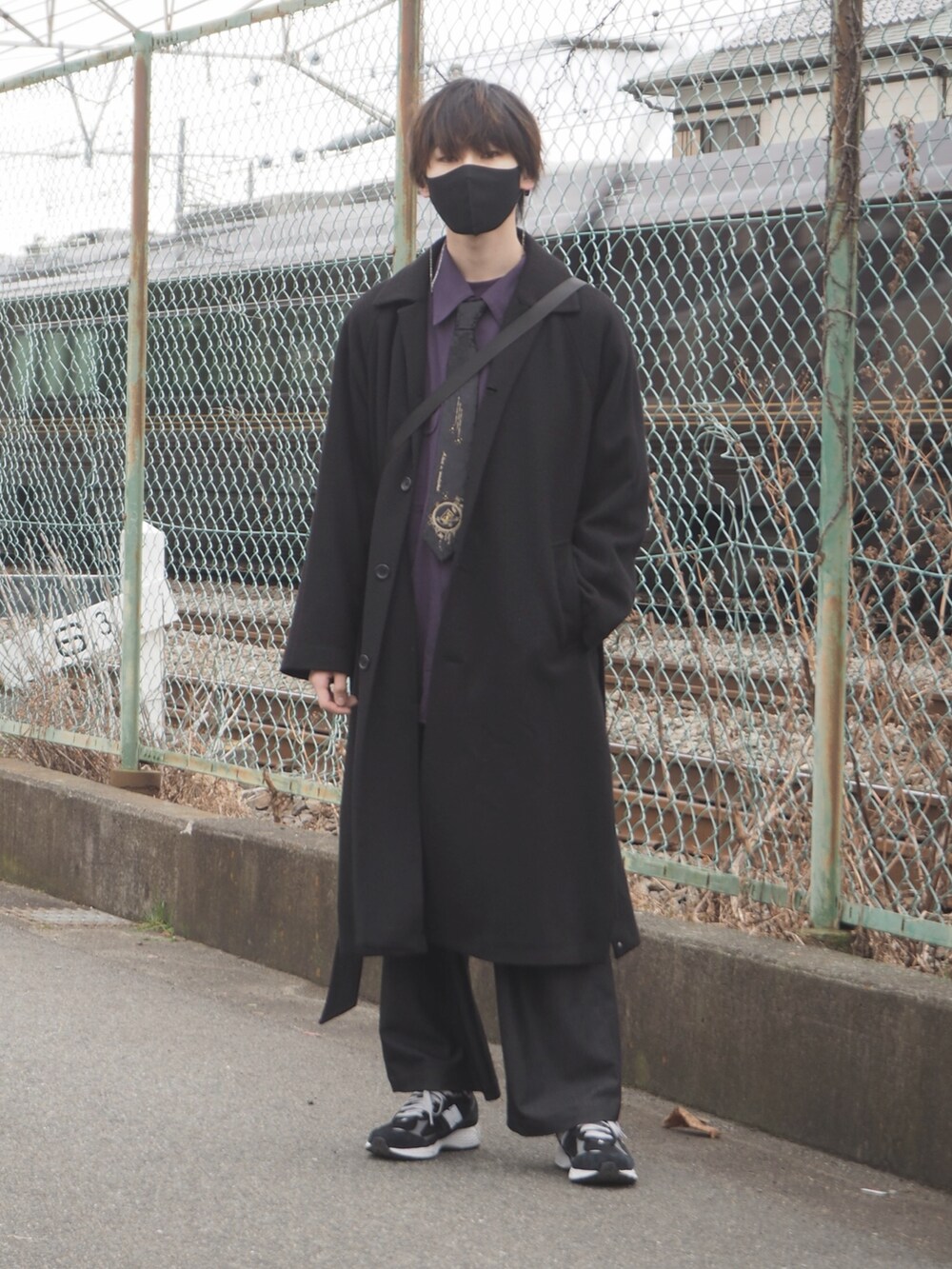 ブラック系のチェスターコート、ブルー系のデニムパンツ、ブラック系のスニーカーを着用したメンズの冬コーディネートの5枚目の写真