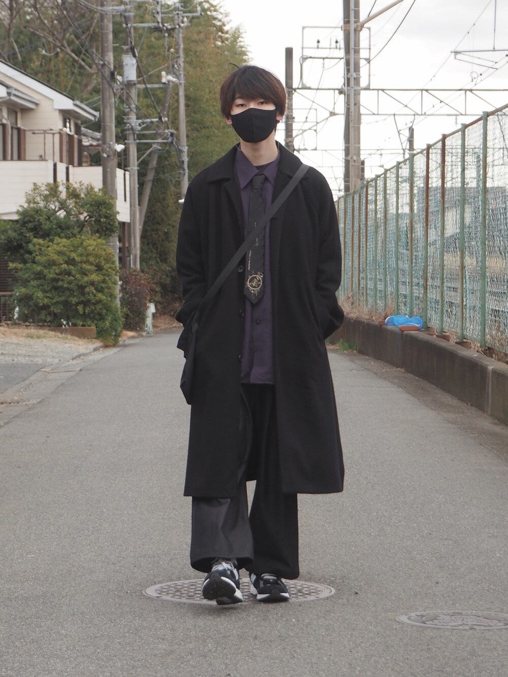 ブラック系のチェスターコート、ブルー系のデニムパンツ、ブラック系のスニーカーを着用したメンズの冬コーディネートの3枚目の写真