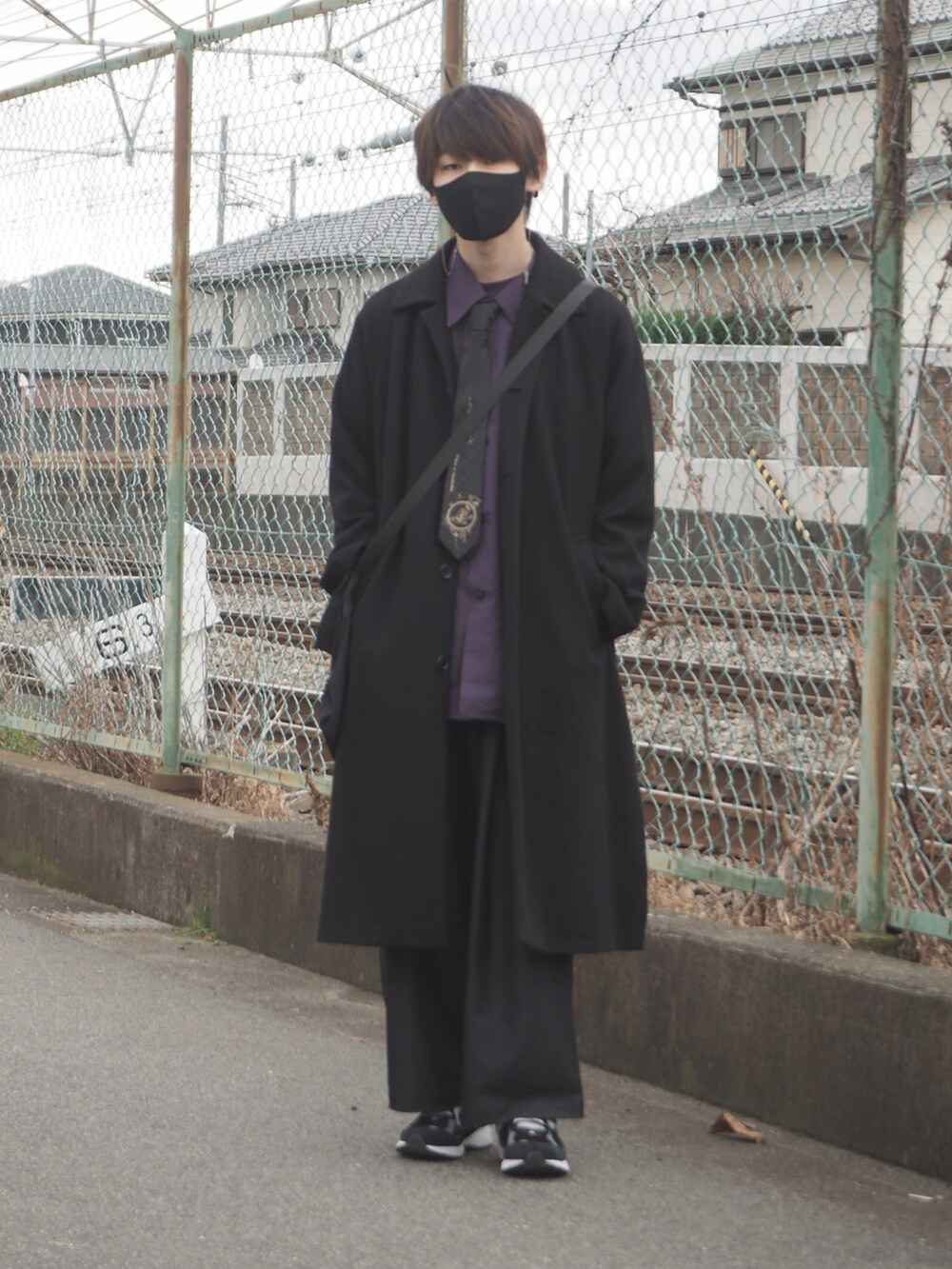 ブラック系のチェスターコート、ブルー系のデニムパンツ、ブラック系のスニーカーを着用したメンズの冬コーディネートの2枚目の写真