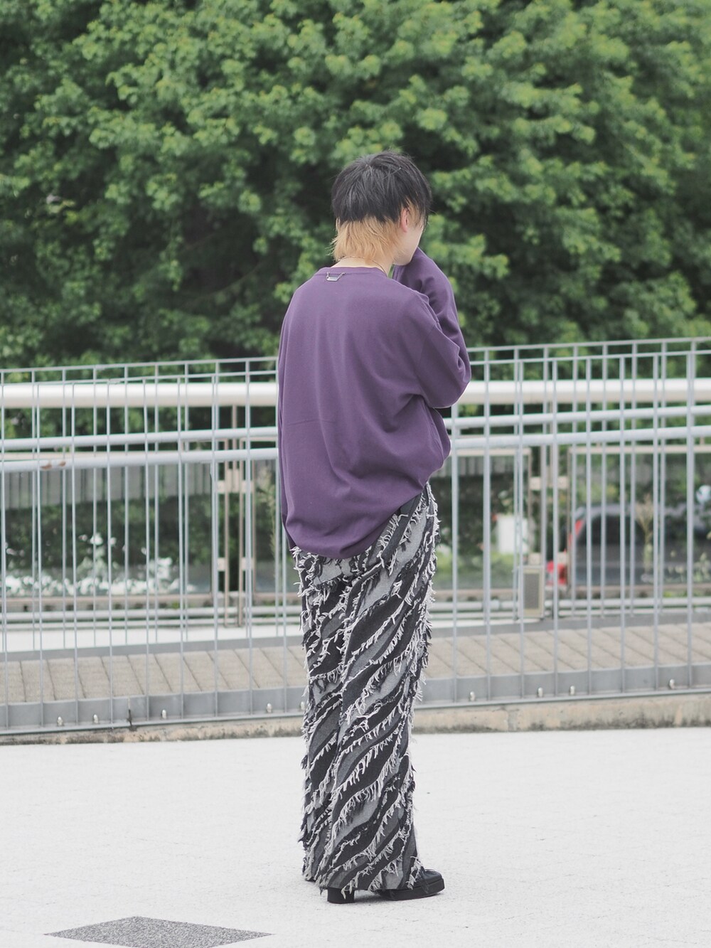 ブラック系のデニムパンツ、パープル系のTシャツ/カットソー、ブラック系のブーツを着用したメンズの秋コーディネートの3枚目の写真