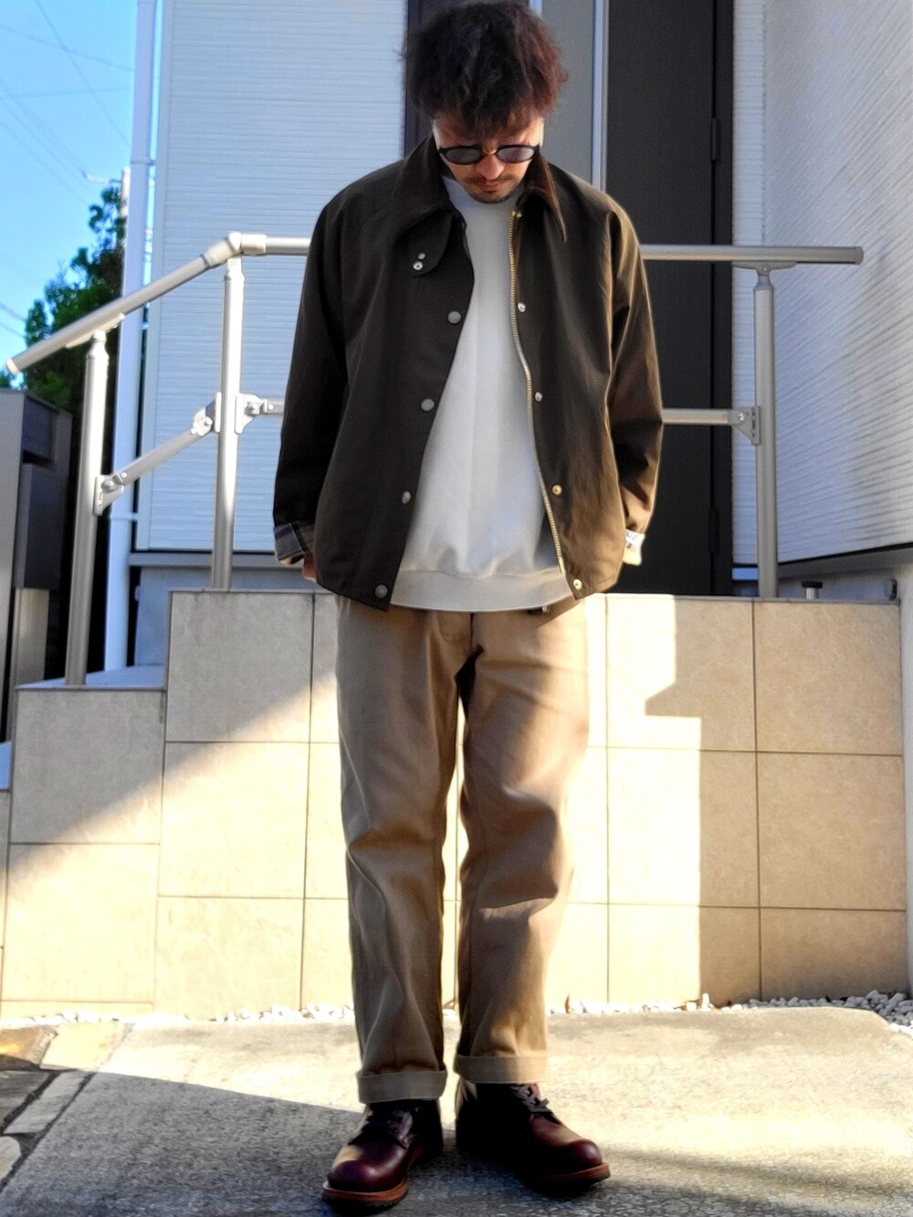 レッド系のブーツ、ベージュ系のチノパンツ、グリーン系のブルゾンを着用したメンズの秋コーディネートの2枚目の写真