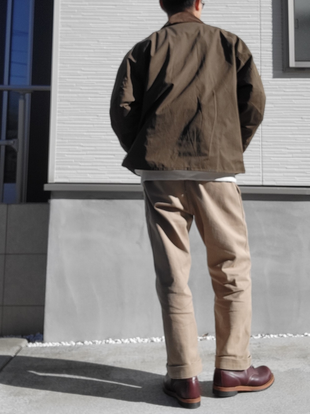 レッド系のブーツ、ベージュ系のチノパンツ、グリーン系のブルゾンを着用したメンズの秋コーディネートの3枚目の写真