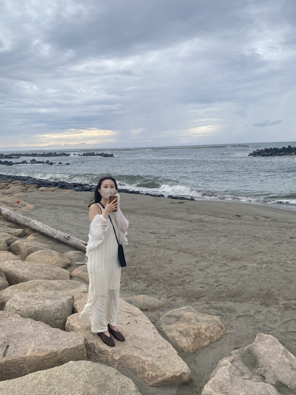 ベージュ系のワンピース、ホワイト系のナイロンジャケットを着用したレディースの秋コーディネートの3枚目の写真