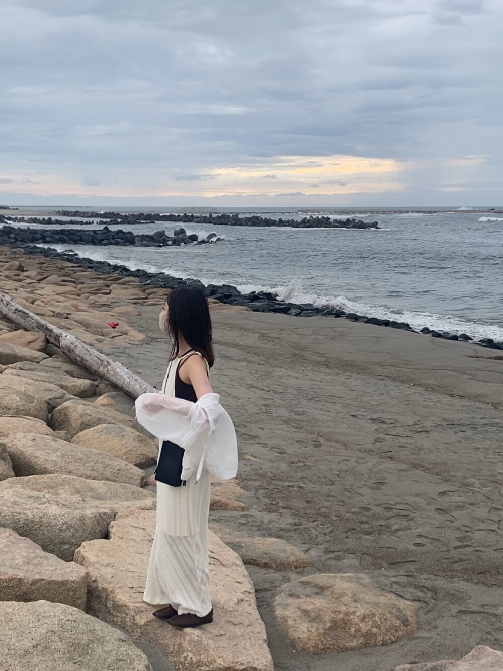 ベージュ系のワンピース、ホワイト系のナイロンジャケットを着用したレディースの秋コーディネートの2枚目の写真