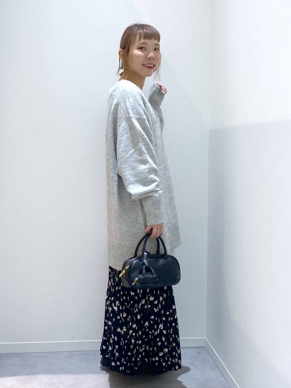 グレー系のニット/セーター、ホワイト系のTシャツ/カットソー、ブラック系のハンドバッグを着用したレディースの秋コーディネートの4枚目の写真