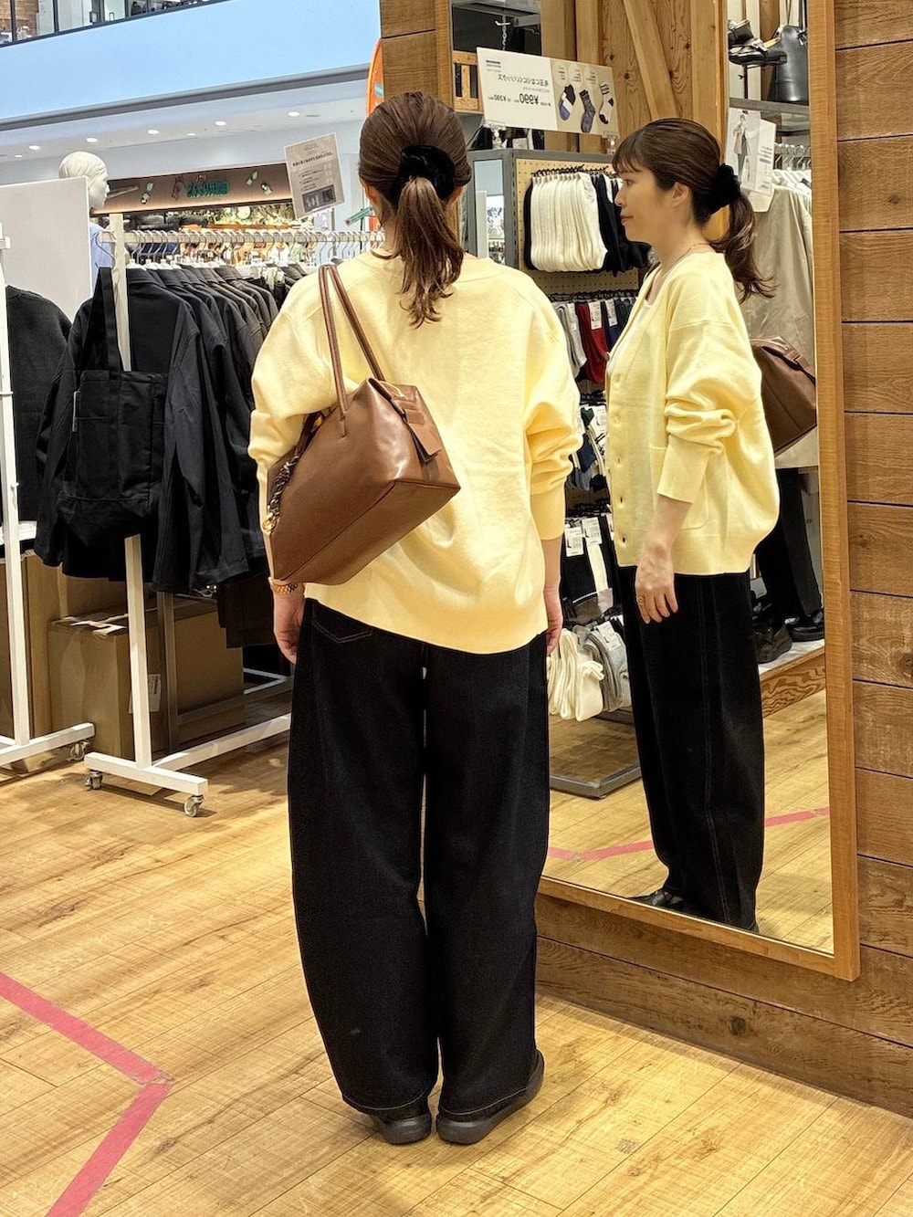 ブラウン系のボストンバッグ、ブルー系のデニムパンツ、イエロー系のカーディガン/ボレロを着用したレディースの春コーディネートの3枚目の写真