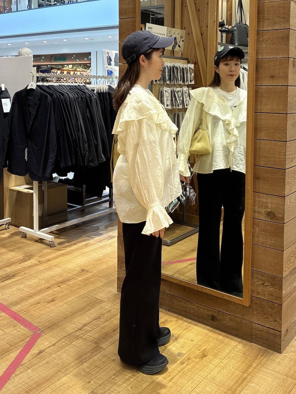 イエロー系のショルダーバッグ、ブラック系のスウェットパンツ、ホワイト系のシャツ/ブラウスを着用したレディースの春コーディネートの2枚目の写真