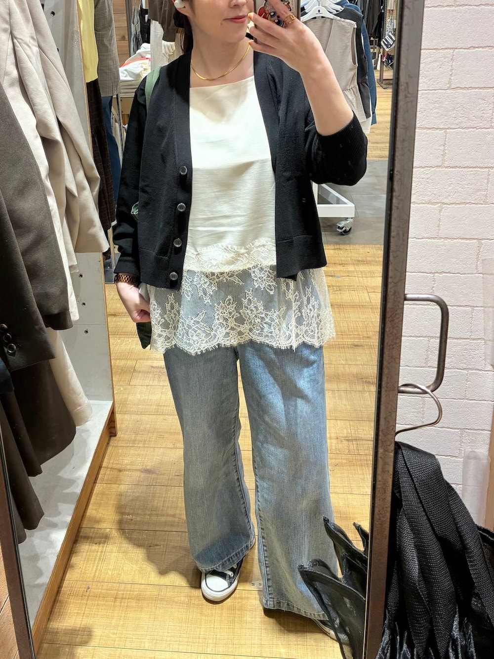 ブルー系のデニムパンツ、ブラック系のカーディガン/ボレロ、ホワイト系のキャミソールを着用したレディースの春コーディネートの4枚目の写真